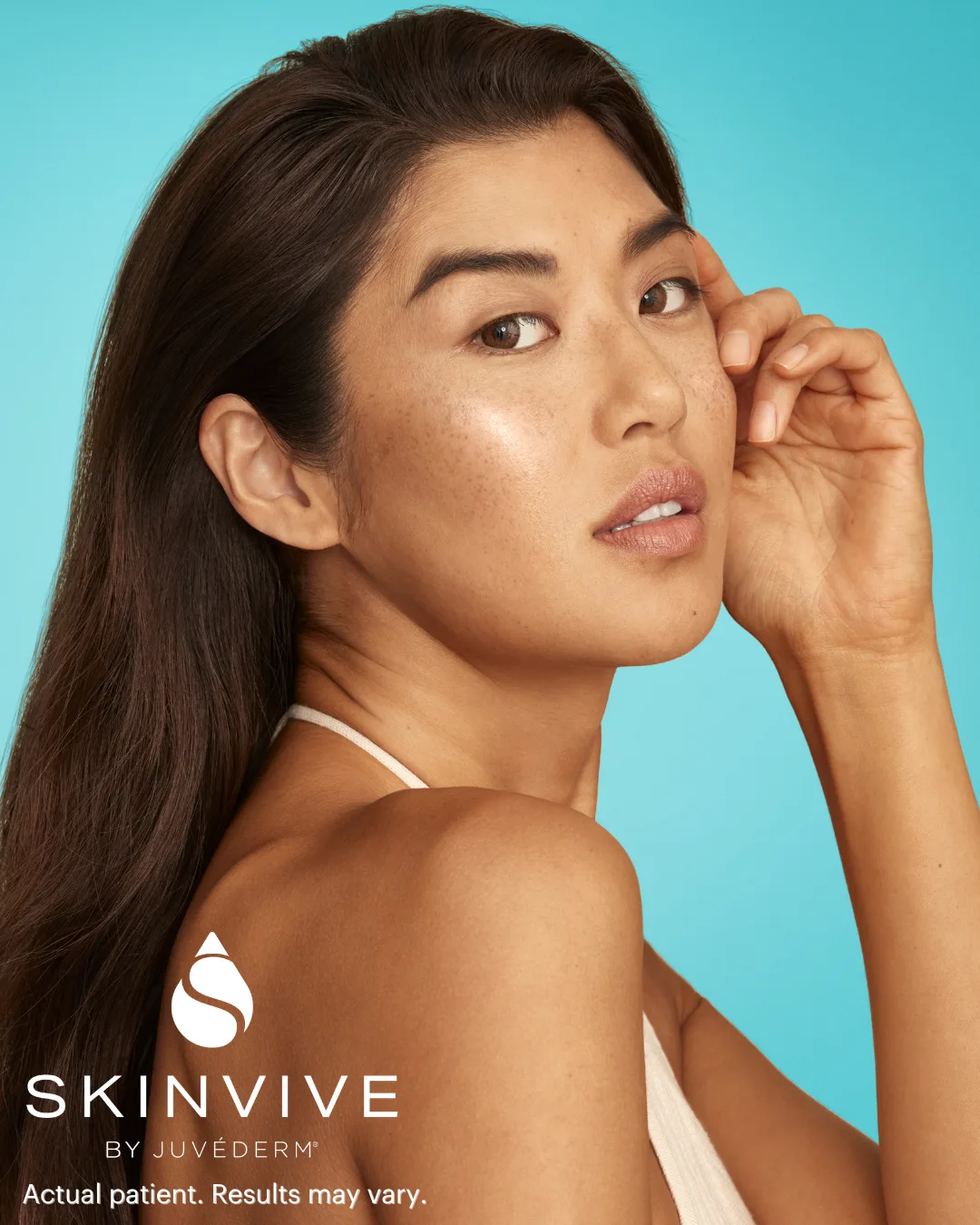 Retrato de una paciente de SKINVIVE™ by JUVÉDERM® de Allergan con una mano junto a la mejilla