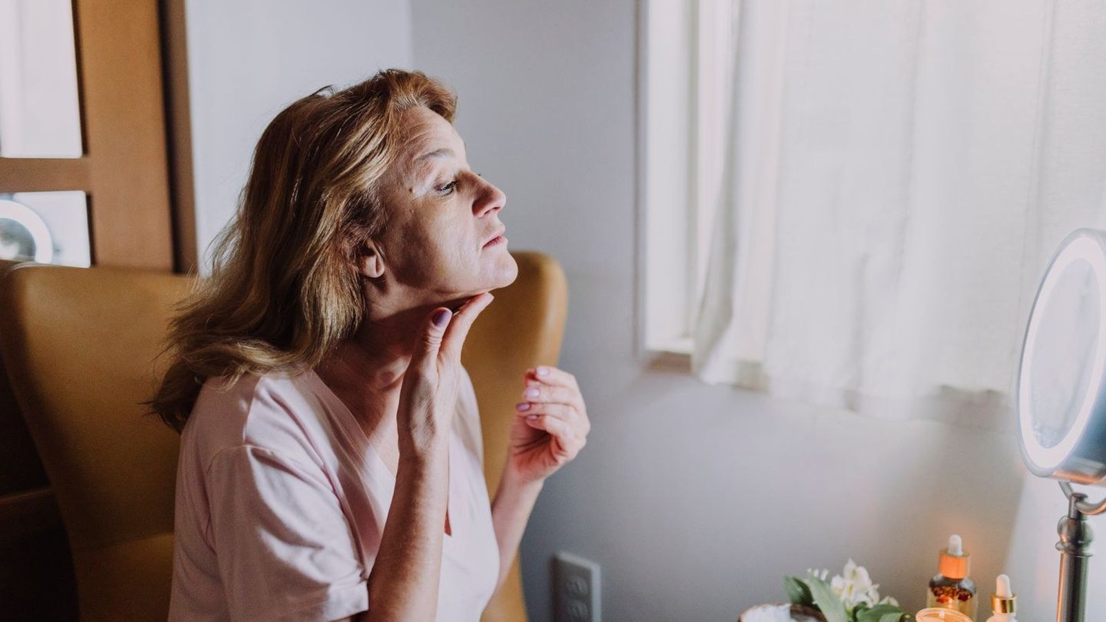 Mature woman applying skincare at her vanity during her evening routine